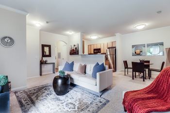 A living room with a white couch and a red chair.